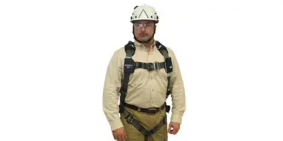 A worker wearing the fully adjusted harness and a white safety helmet is standing and looking directly at the camera. This final step involves verifying that all straps are snug, buckle connections are secure, and the back D-ring is correctly centered.