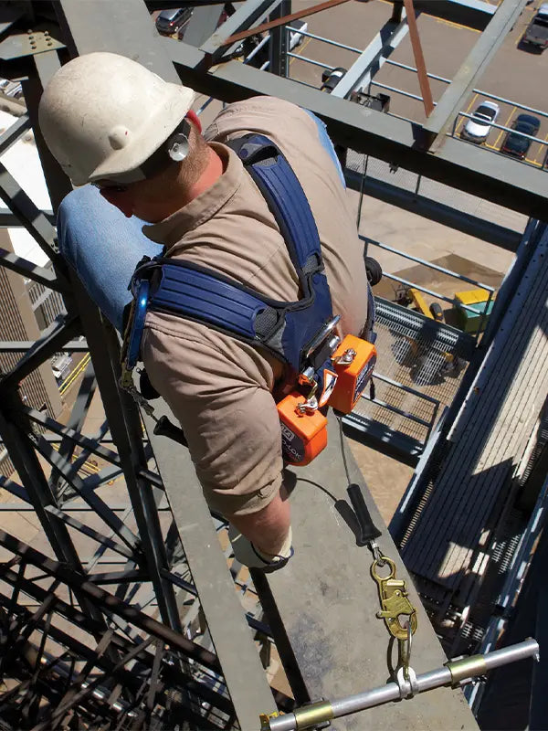 A worker on a tall steel structure utilizes a full-body 3M safety harness and lanyard. This setup shows fall arrest equipment properly attached while navigating the height.